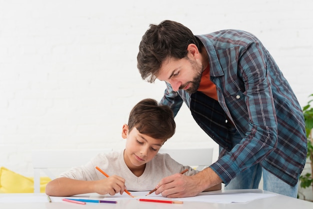 Father looking at his son doing homework