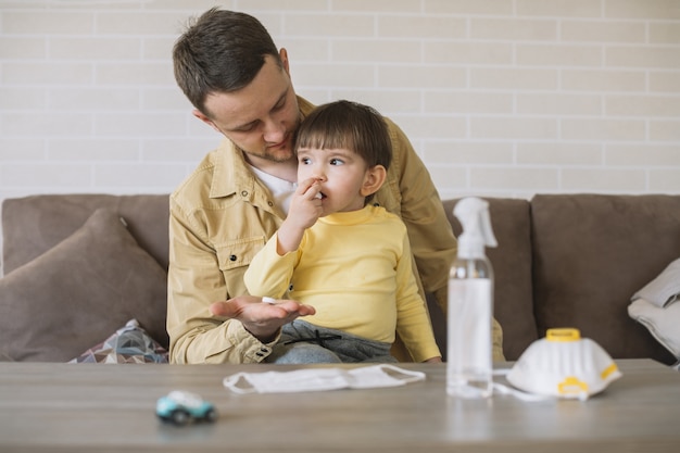 father looking at his son and medical mask on table