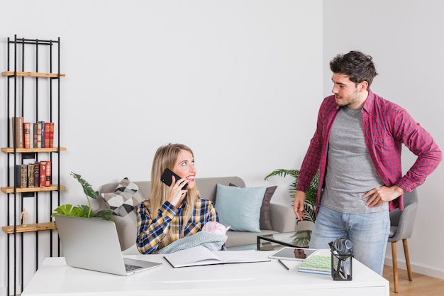 Father looking at mother with baby talking on phone 