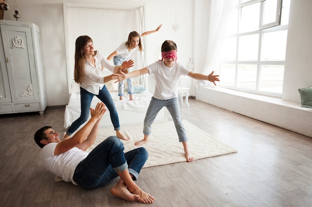 Father lying on floor while family playing blind man's buff at home