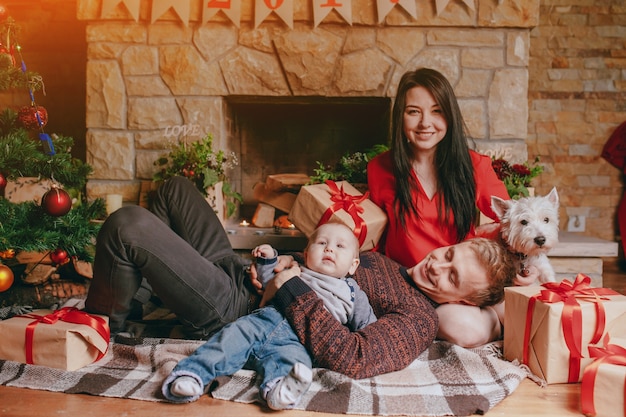 Father lying on the lap of his wife while holding the baby with one arm