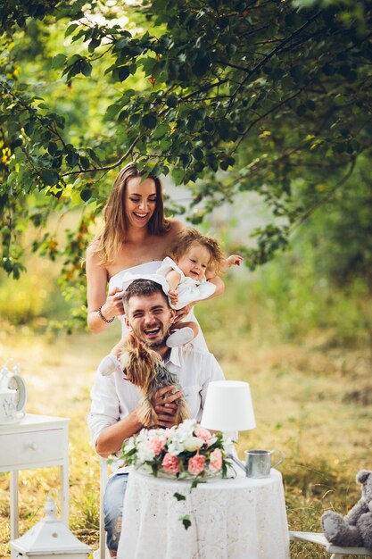 Father and mother with their daughter in the middle of the field with white table and chairs