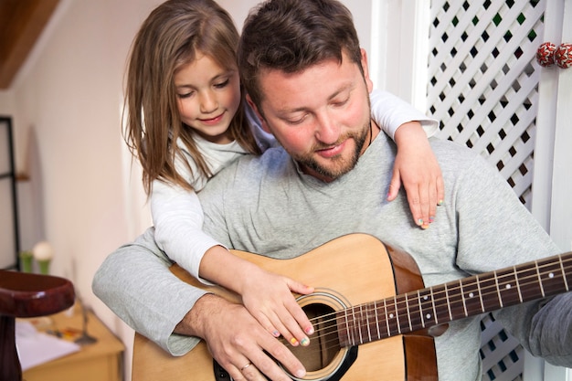 Отец играет на гитаре со своей дочерью