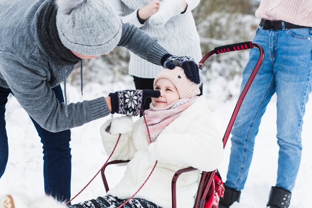 Father playing with daughter in sleigh