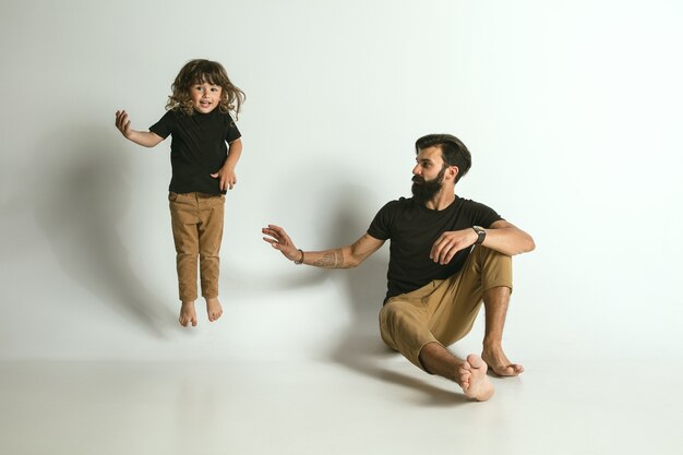 Father playing with young son against white