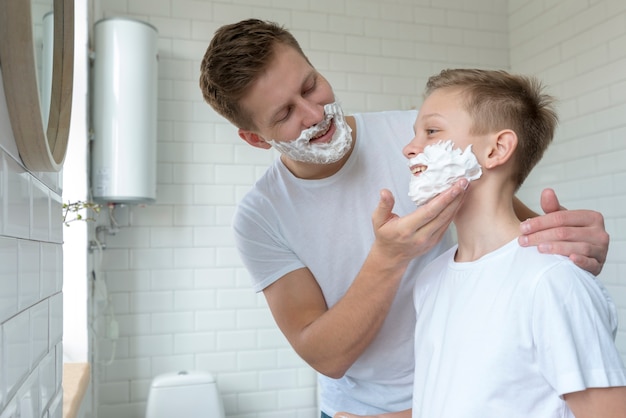 Father puts shaving cream on son's face