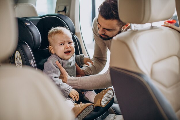 Father putting daughter in a car seat