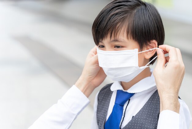 그의 아들, 보호를 위해 얼굴 마스크를 착용하는 아시아 가족에게 보호 마스크를 씌우는 아버지