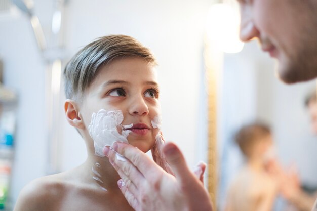 Father putting shaving foam on his son's face