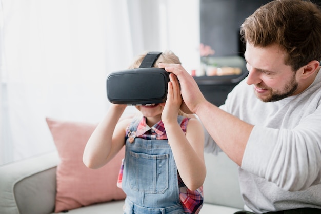 Father putting VR glasses on daughter