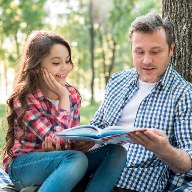 Father reading book for his daughter in park