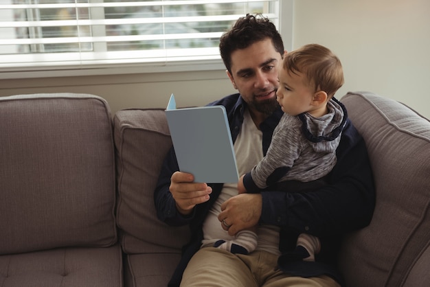 Free photo father reading a book while holding his baby