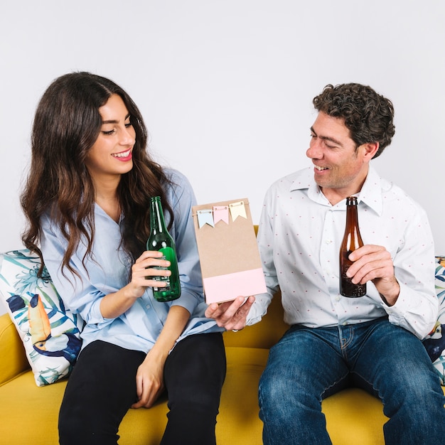 Father receiving present from daughter while drinking beer