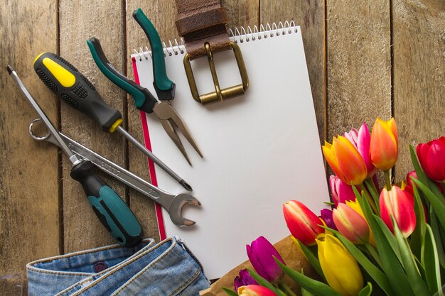 Father's day composition with tools, colored flowers and notebook