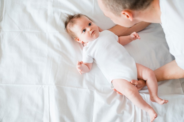 Father softly embracing baby on bed