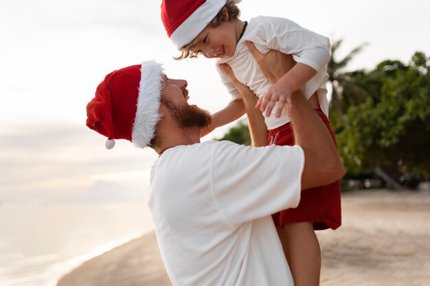 Father and son on the beach with santa hats