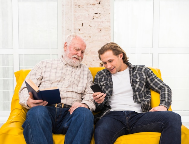 Foto gratuita padre e figlio, navigazione informazioni nel telefono cellulare