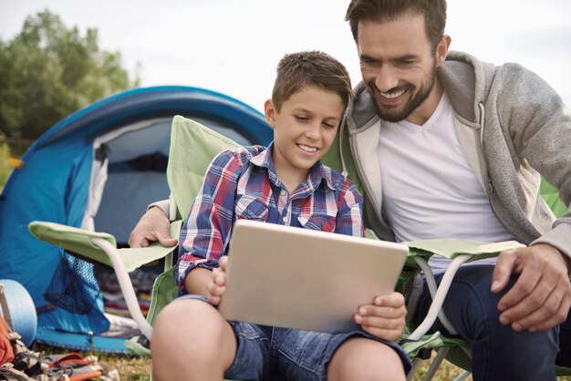 Father and son browsing the Internet on camping