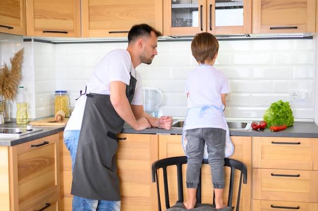 Free photo father and son cooking in the kitchen long view