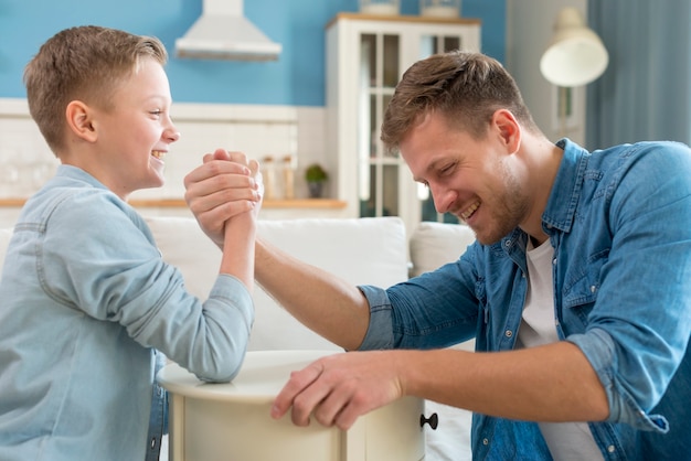 Free photo father and son doing  arm wrestling indoors