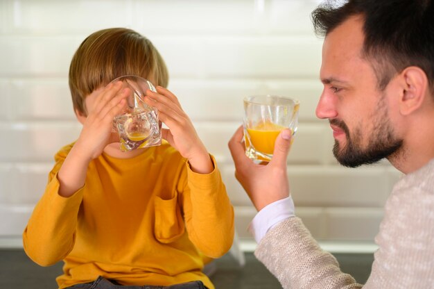 父と息子が台所でオレンジジュースを飲む