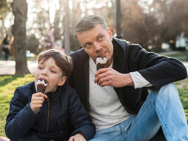 父と息子が公園でアイスクリームを食べる