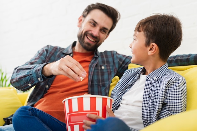 Father and son eating popcorn and looking at each other