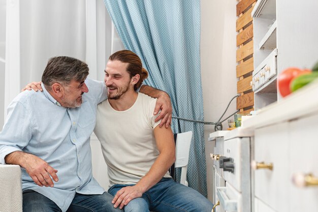 Father and son embracing and talking in kitchen