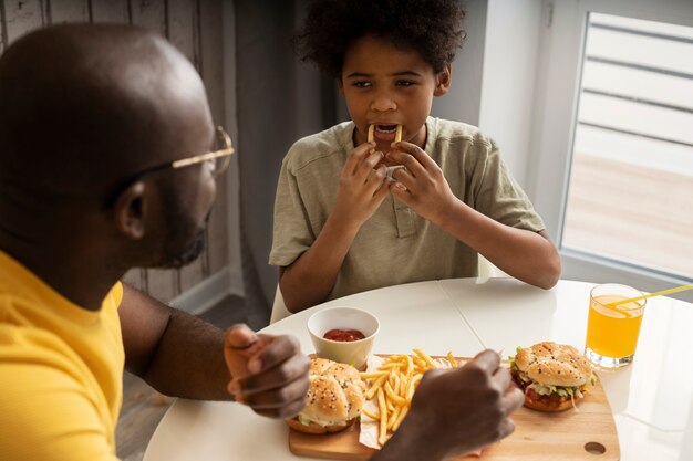 Father and son enjoying burger and fries together at home