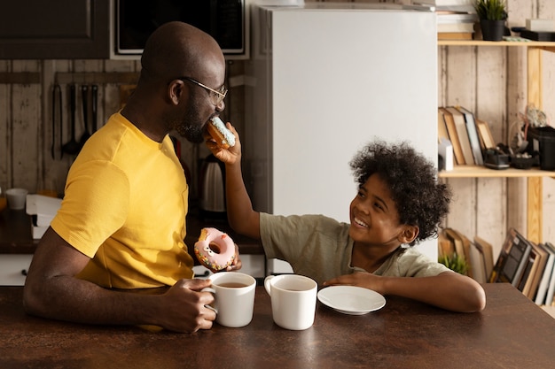 Father and son enjoying donuts and tea together at home