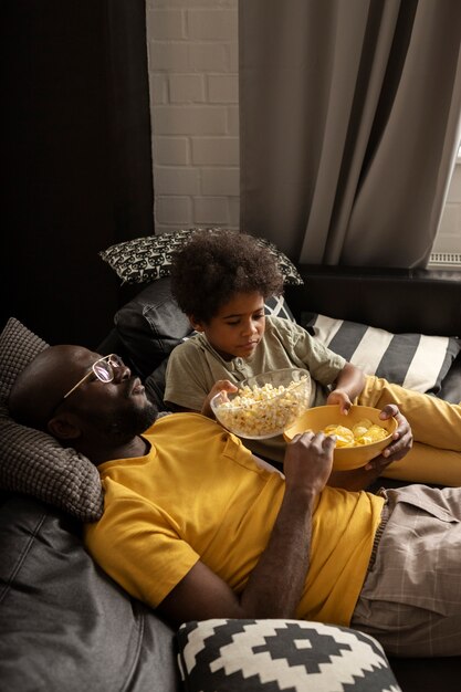 Отец и сын вместе наслаждаются попкорном на диване
