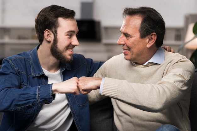 Father and son fist bumping in living room