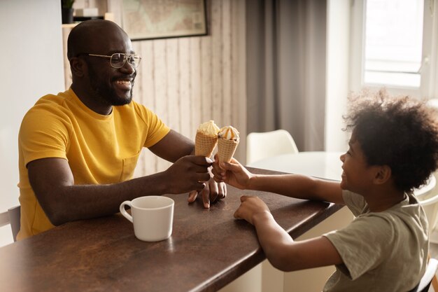 Father and son having ice cream together in the kitchen