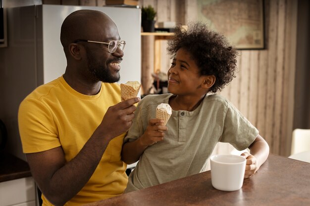 Father and son having ice cream together in the kitchen
