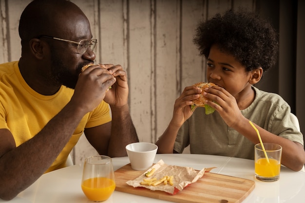 Father and son having lunch together and enjoying burgers and fries