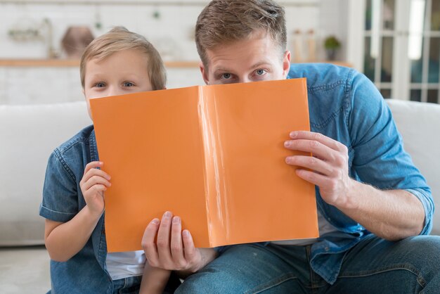 Father and son hiding behind a notebook