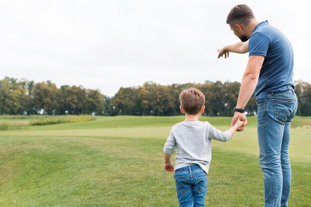 Father and son holding hands from behind shot