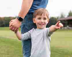 Foto gratuita padre e figlio che si tengono per mano nel parco