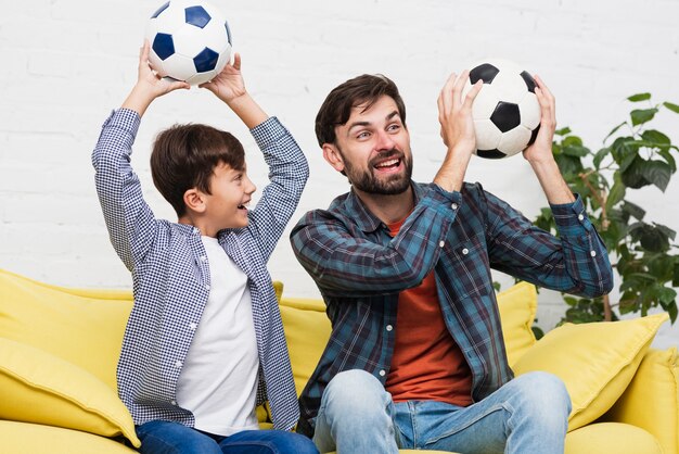 Free photo father and son holding soccer balls