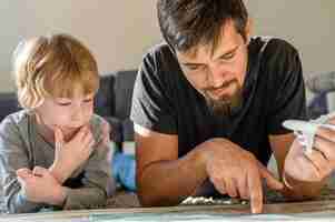 Free photo father and son looking at map together at home