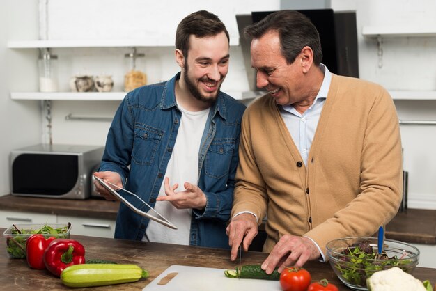 Father and son making salad in kitchen
