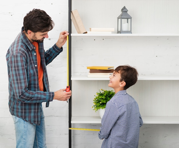 Free photo father and son measuring a shelf