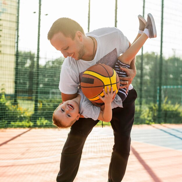 Father and son playing on the basketball field front view