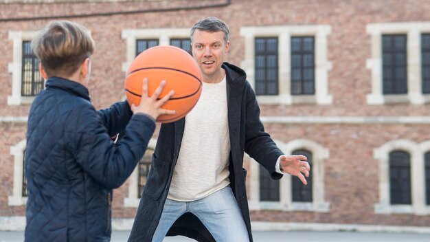 Отец и сын играют в баскетбол через плечо