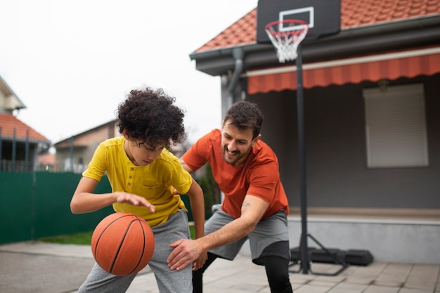 Free photo father and son playing basketball together in the backyard