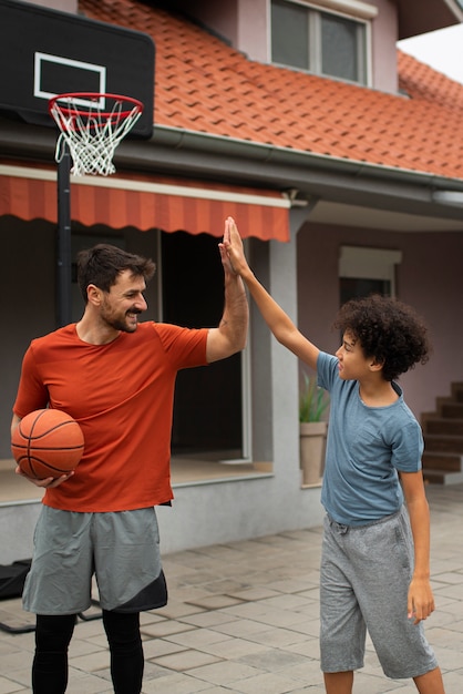 Foto gratuita padre e figlio giocano insieme a basket in giardino