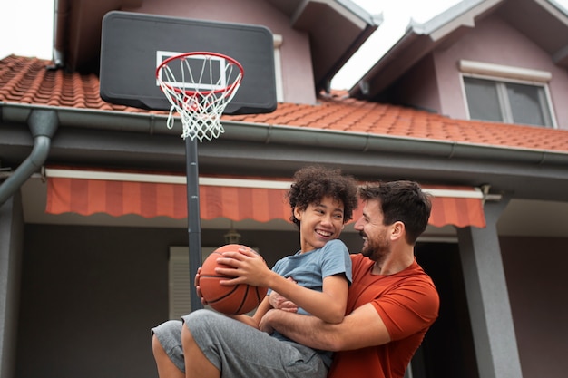 Free photo father and son playing basketball together in the backyard