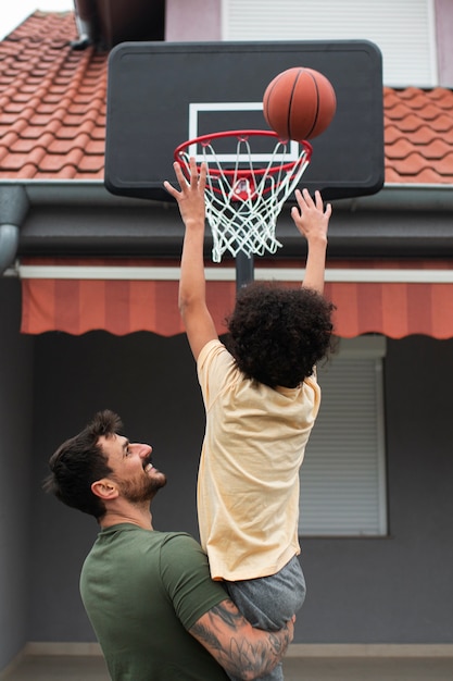 父と息子が家の裏庭で一緒にバスケットボールをしている