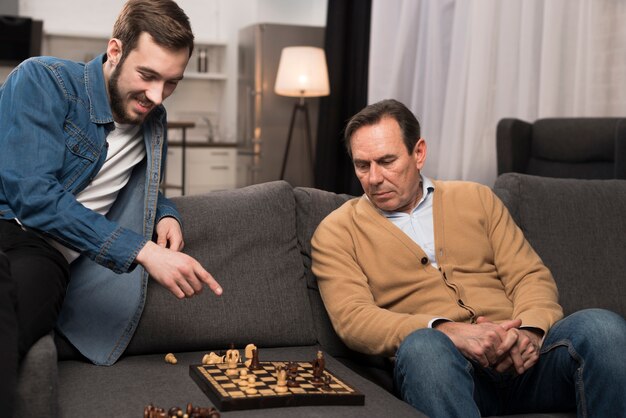 Father and son playing chess in living room