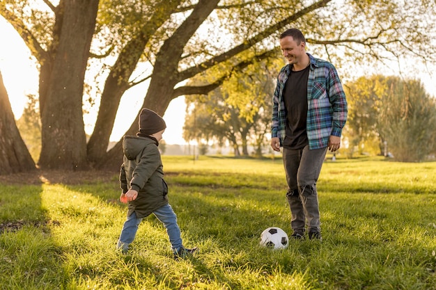 Отец и сын играют в футбол в парке